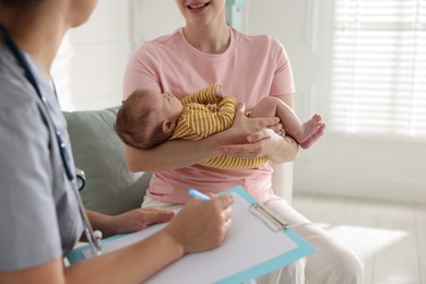 Photo of Mother and her cute baby having appointment with pediatrician in hospital, closeup