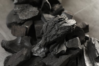 Photo of Pieces of black coals on grey table, closeup