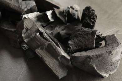 Photo of Pieces of black coals on grey table, closeup