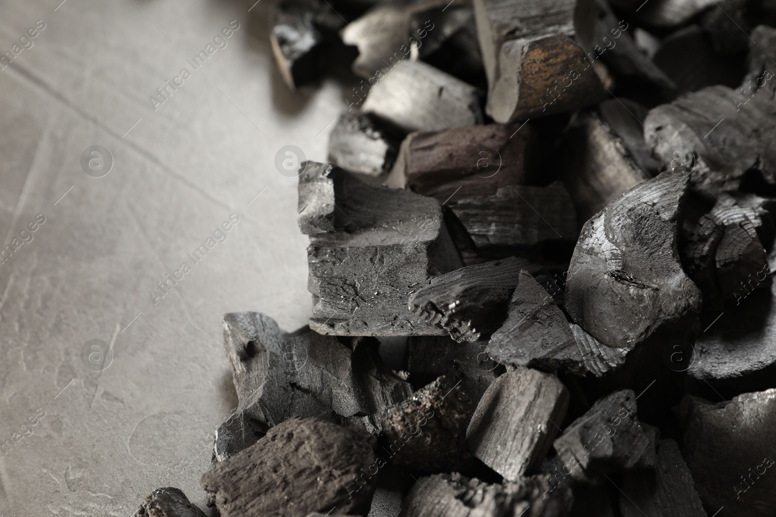 Pieces of black coals on grey table, closeup. Space for text Photo of Pieces of black coals on grey table, closeup. Space for text