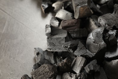 Photo of Pieces of black coals on grey table, closeup. Space for text