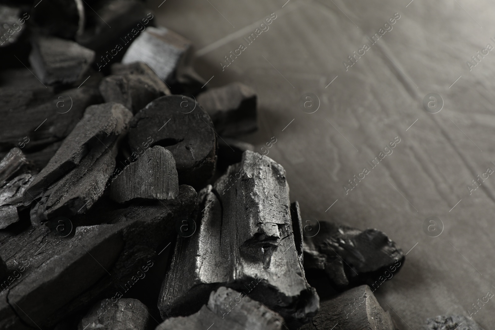Pieces of black coals on grey table, closeup. Space for text Photo of Pieces of black coals on grey table, closeup. Space for text