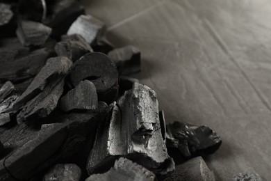 Photo of Pieces of black coals on grey table, closeup. Space for text