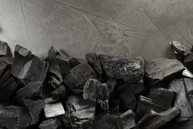 Photo of Pieces of black coals on grey table, flat lay. Space for text