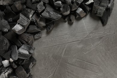 Photo of Pieces of black coals on grey table, flat lay. Space for text