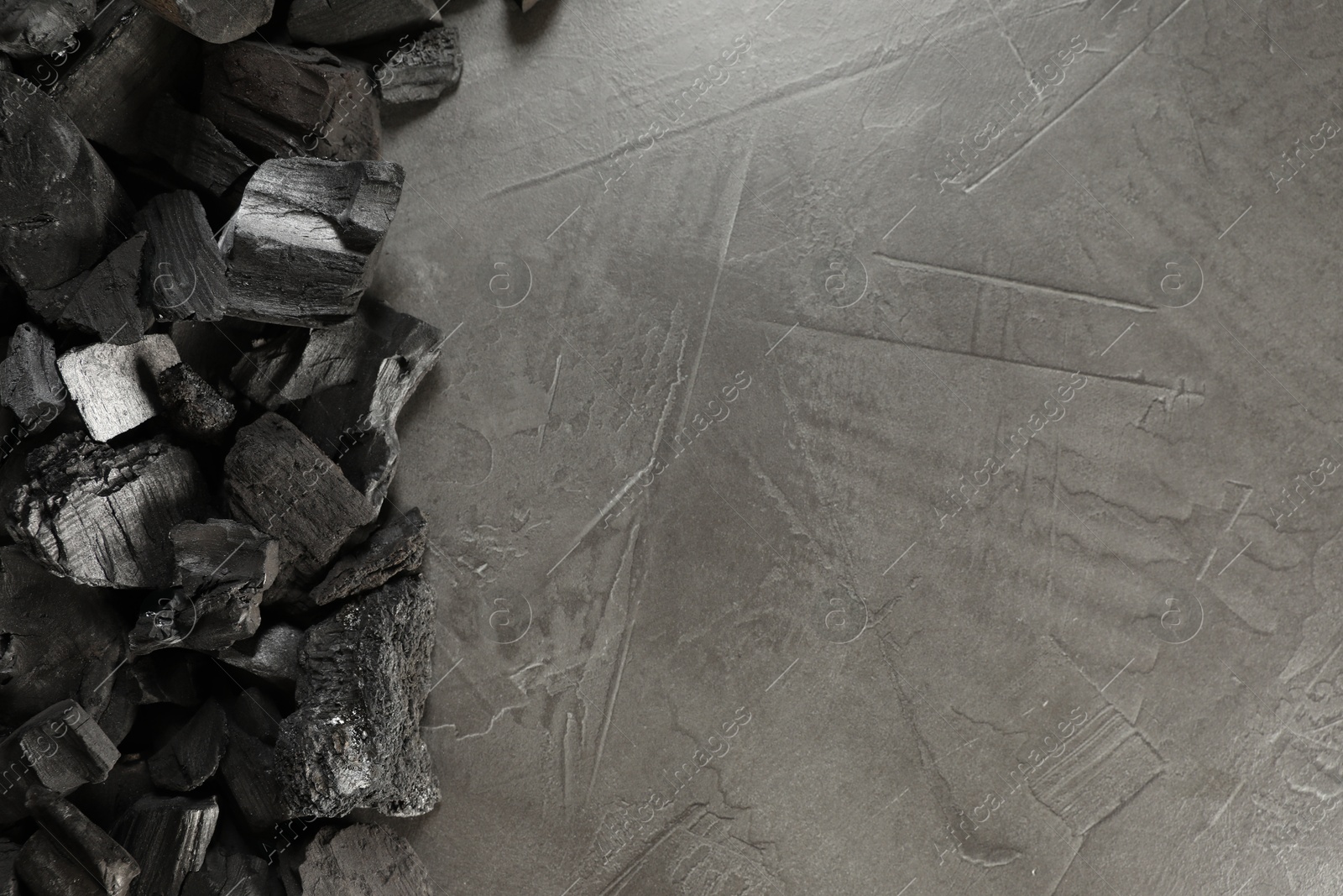 Pieces of black coals on grey table, flat lay. Space for text Photo of Pieces of black coals on grey table, flat lay. Space for text