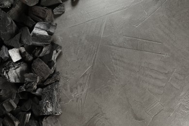 Photo of Pieces of black coals on grey table, flat lay. Space for text