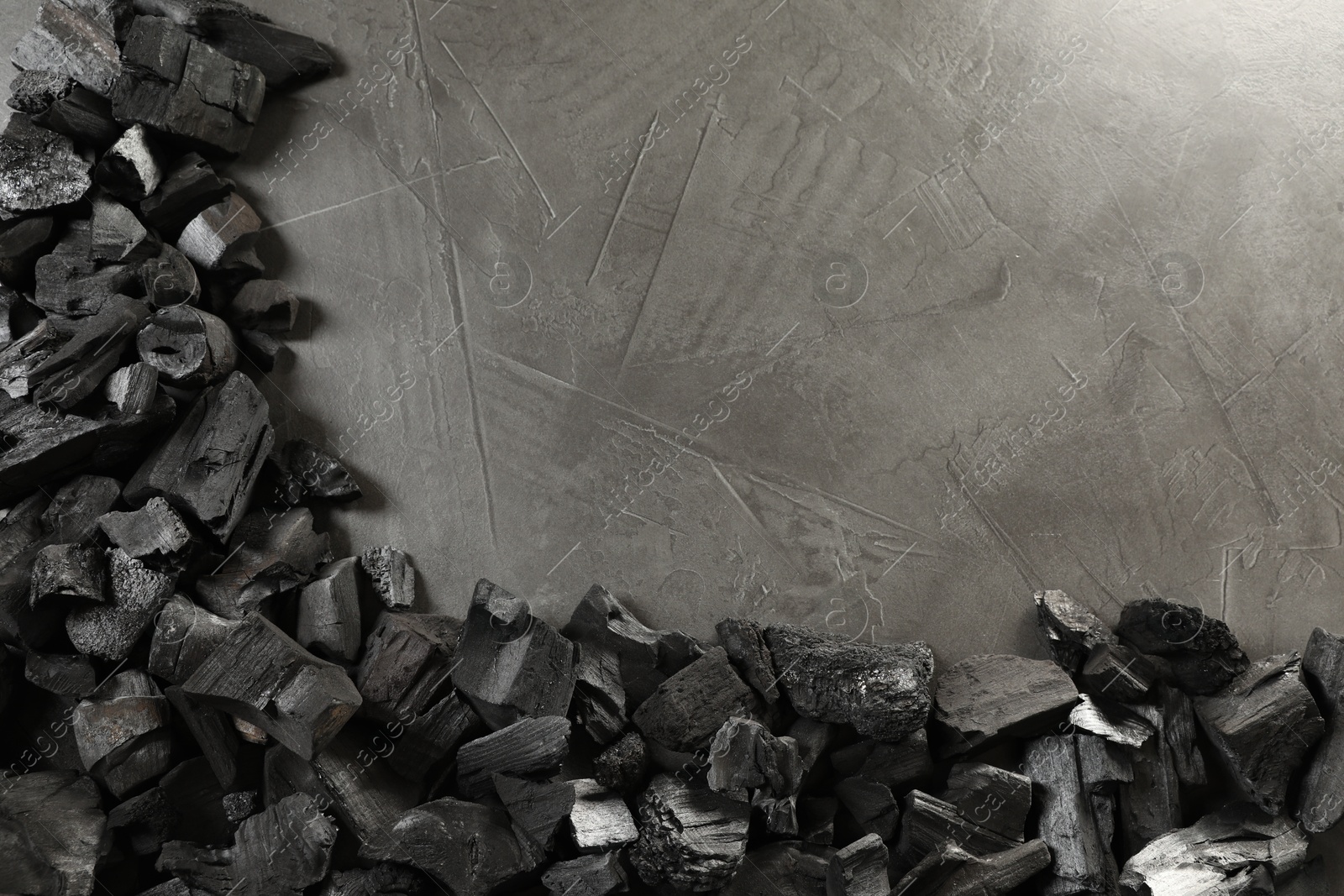 Pieces of black coals on grey table, flat lay. Space for text Photo of Pieces of black coals on grey table, flat lay. Space for text
