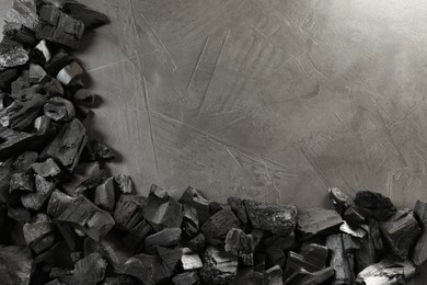 Photo of Pieces of black coals on grey table, flat lay. Space for text