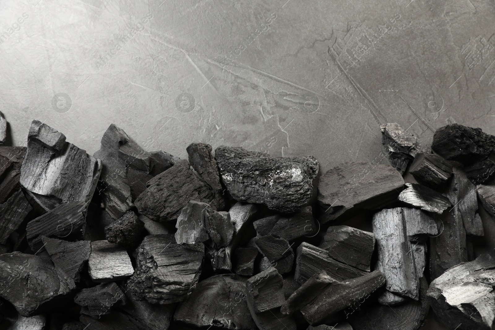 Pieces of black coals on grey table, flat lay. Space for text Photo of Pieces of black coals on grey table, flat lay. Space for text