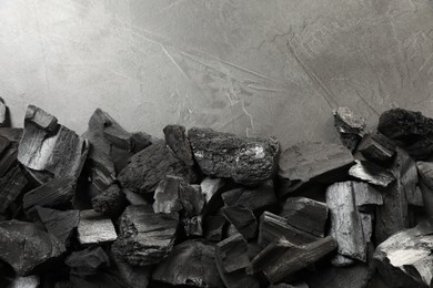 Photo of Pieces of black coals on grey table, flat lay. Space for text