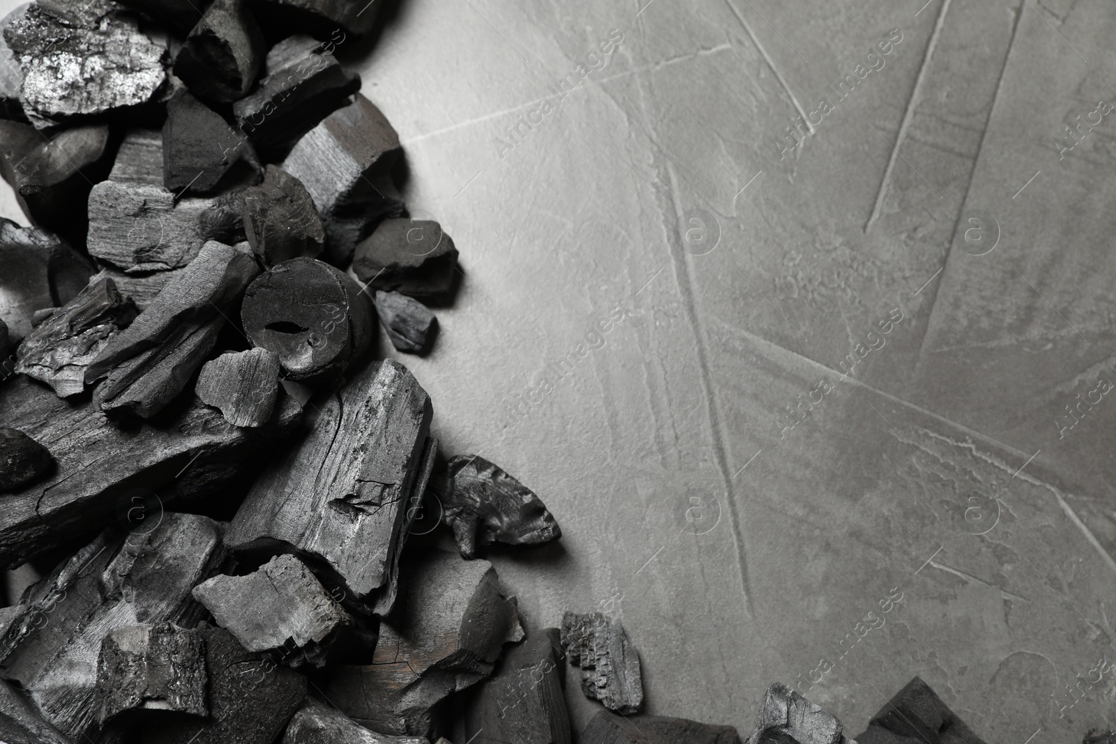 Pieces of black coals on grey table, flat lay. Space for text Photo of Pieces of black coals on grey table, flat lay. Space for text