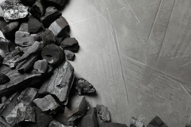 Photo of Pieces of black coals on grey table, flat lay. Space for text