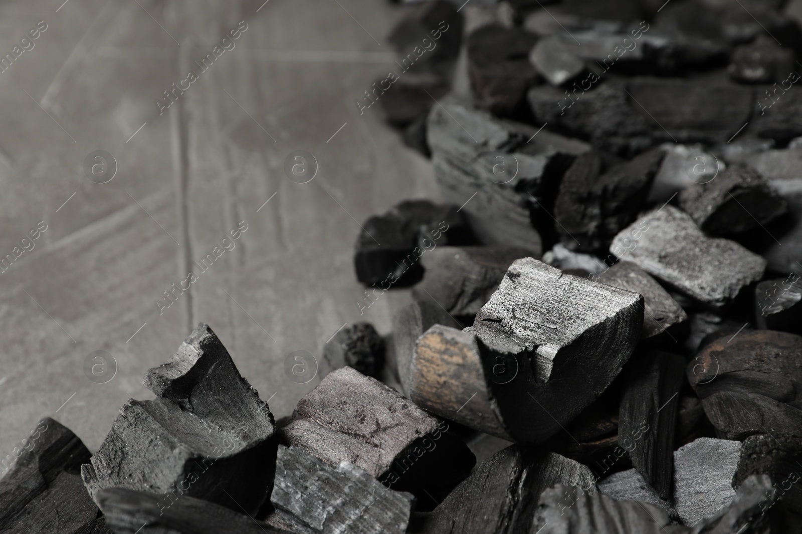 Pieces of black coals on grey table, closeup. Space for text Photo of Pieces of black coals on grey table, closeup. Space for text
