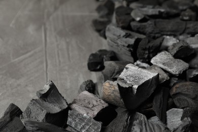 Photo of Pieces of black coals on grey table, closeup. Space for text
