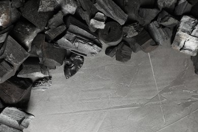 Photo of Pieces of black coals on grey table, flat lay. Space for text