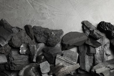Photo of Pieces of black coals on grey table, flat lay