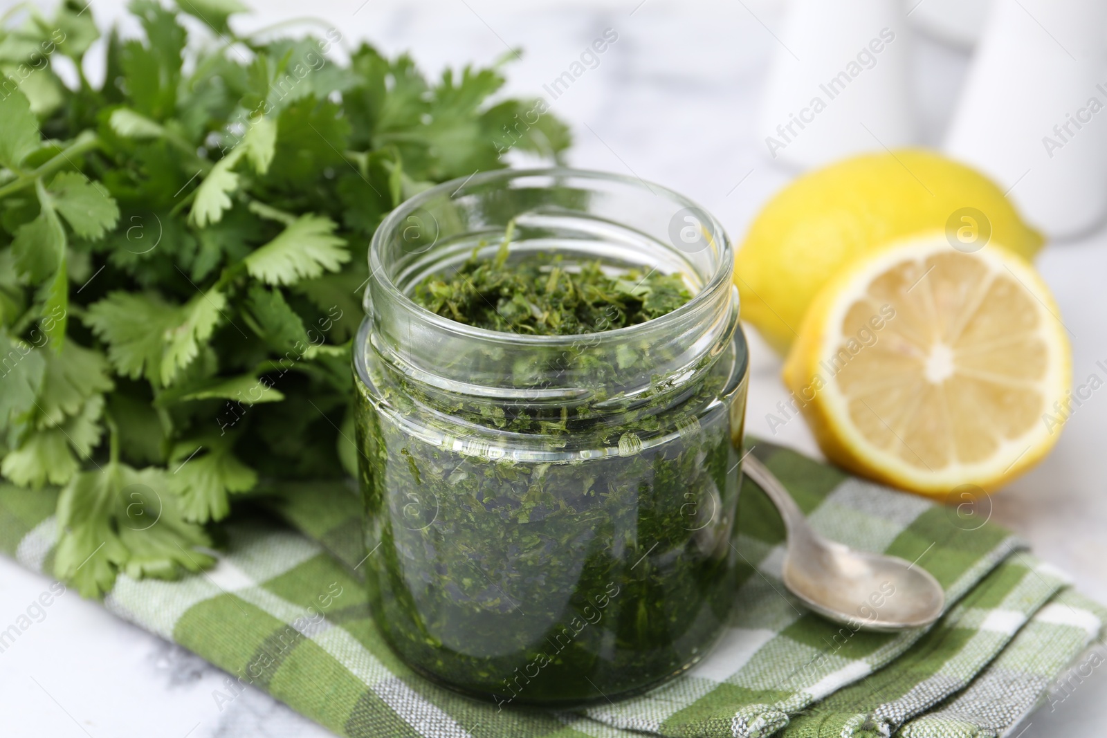 Tasty sauce with cilantro and lemons on white marble table, closeup Photo of Tasty sauce with cilantro and lemons on white marble table, closeup