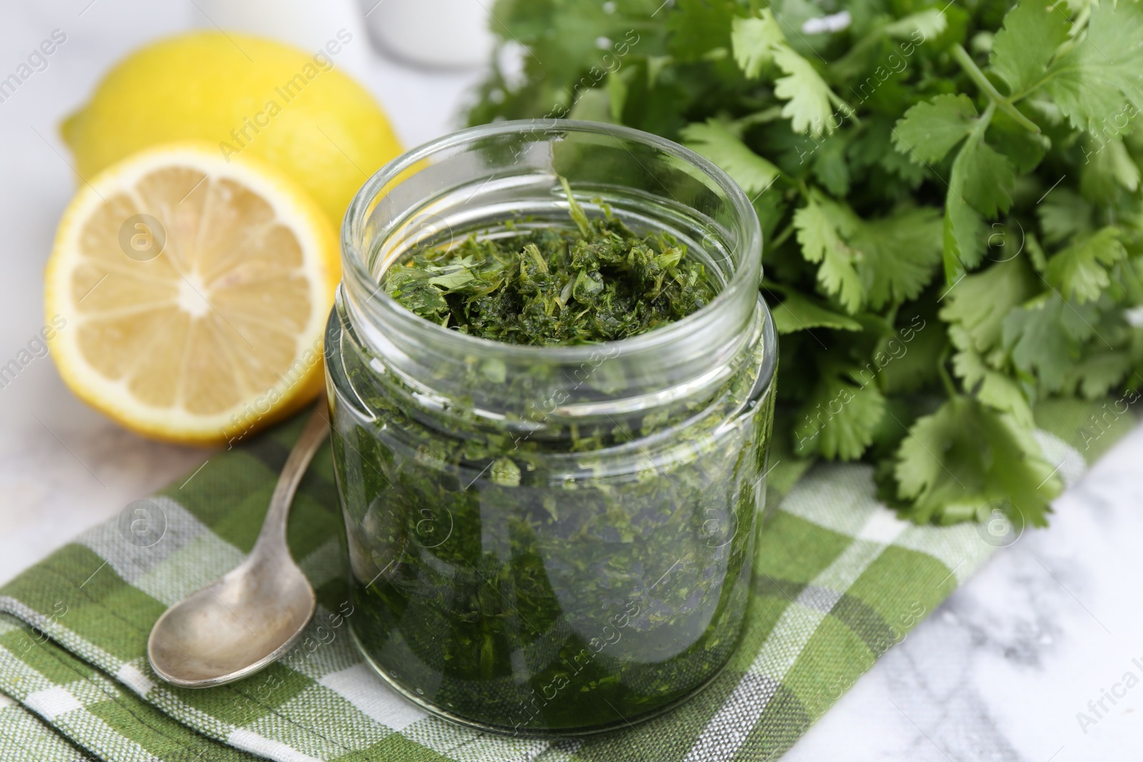 Tasty sauce with cilantro and lemons on white marble table, closeup Photo of Tasty sauce with cilantro and lemons on white marble table, closeup