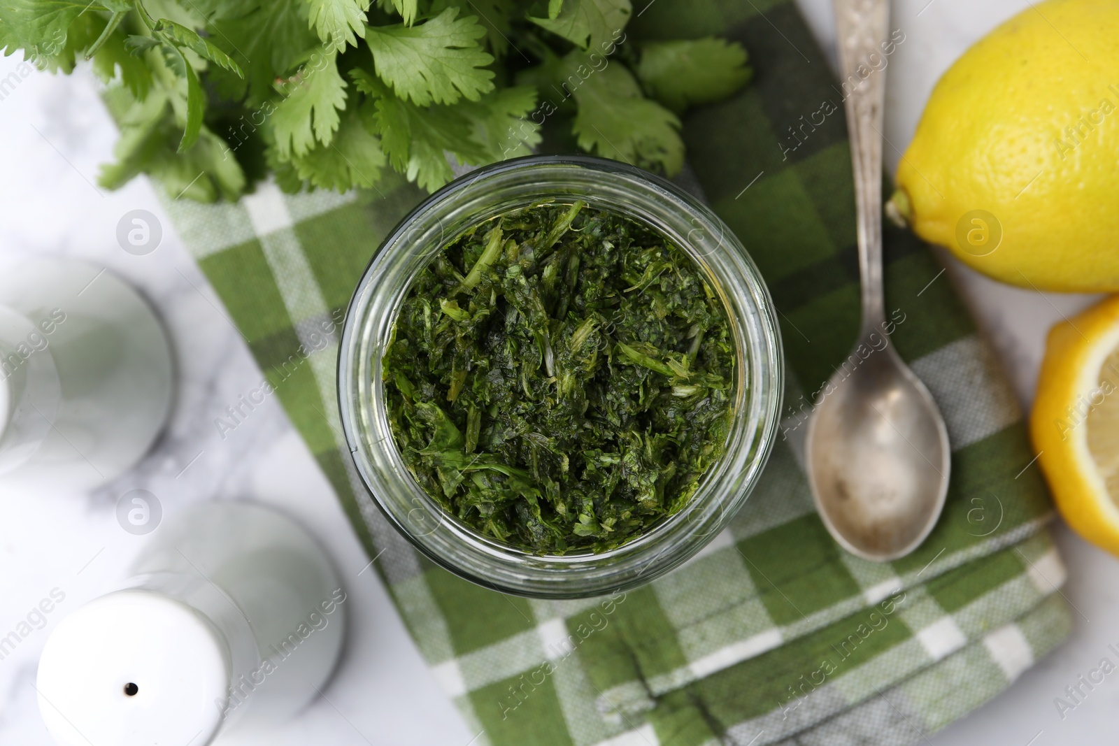 Tasty sauce with cilantro and lemons on white marble table, flat lay Photo of Tasty sauce with cilantro and lemons on white marble table, flat lay