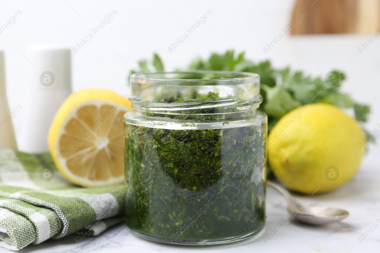 Tasty sauce with cilantro and lemons on white marble table, closeup Photo of Tasty sauce with cilantro and lemons on white marble table, closeup