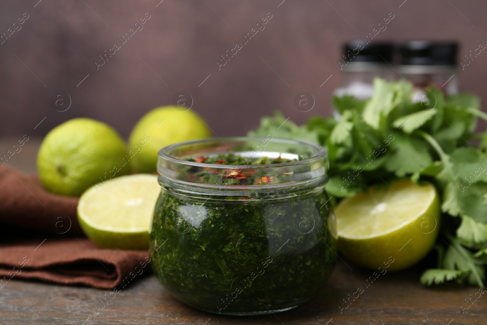 Tasty sauce with cilantro and limes on wooden table, closeup Photo of Tasty sauce with cilantro and limes on wooden table, closeup