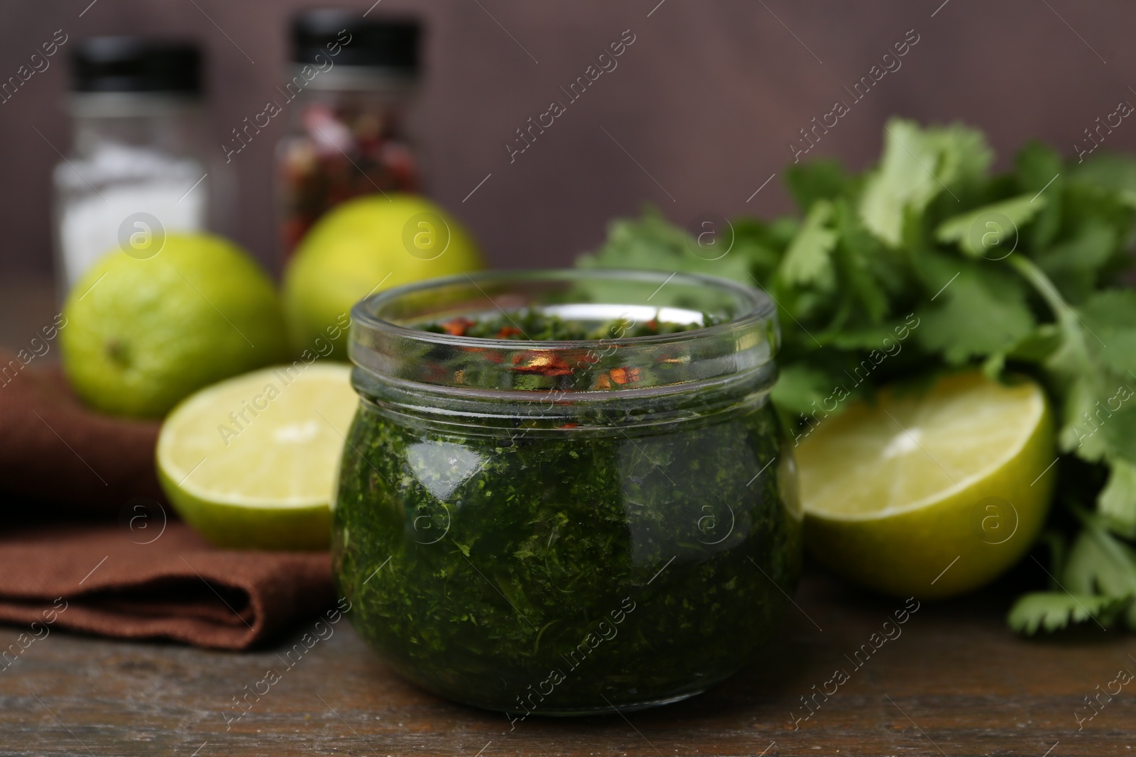 Tasty sauce with cilantro and limes on wooden table, closeup Photo of Tasty sauce with cilantro and limes on wooden table, closeup