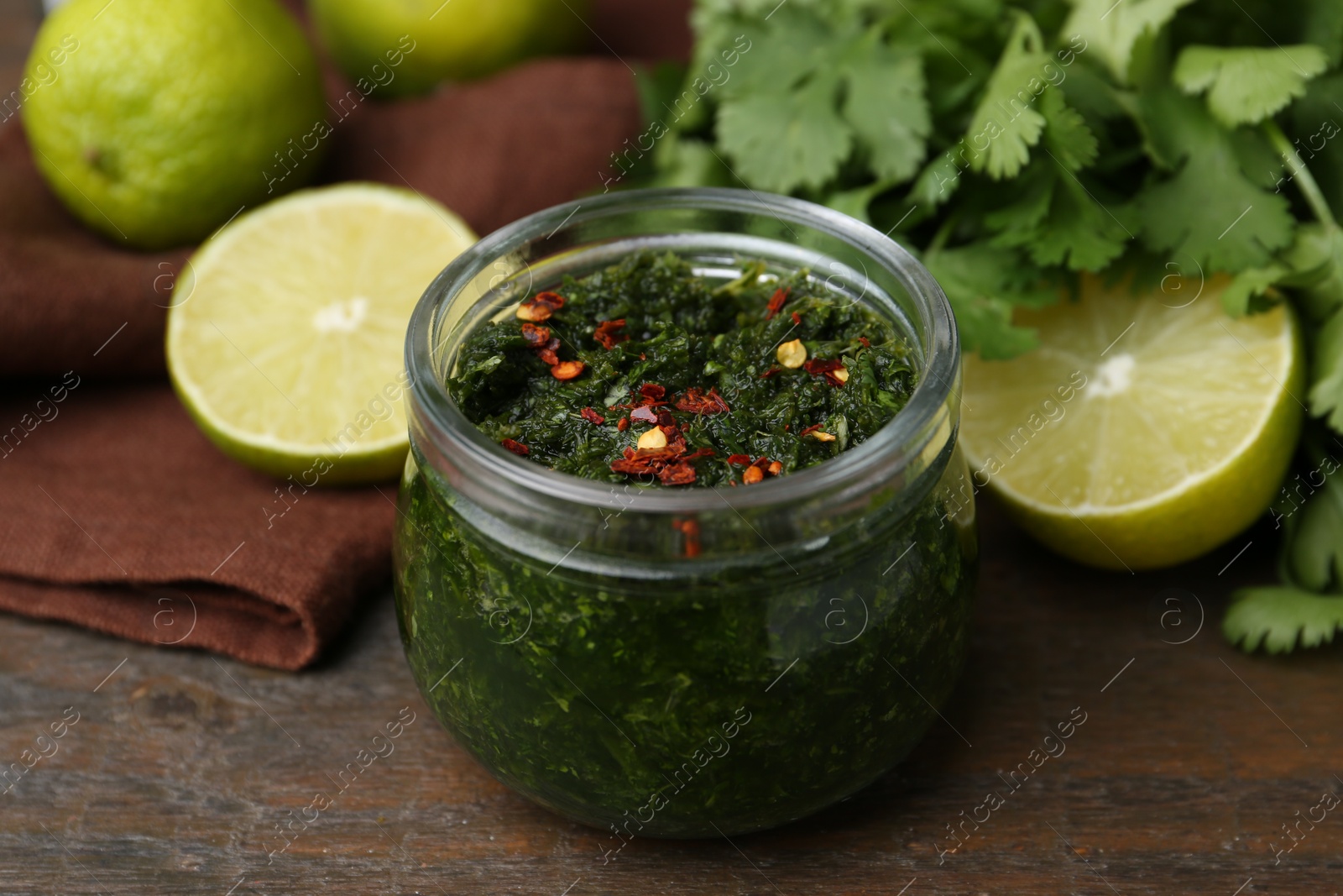 Tasty sauce with cilantro and limes on wooden table, closeup Photo of Tasty sauce with cilantro and limes on wooden table, closeup