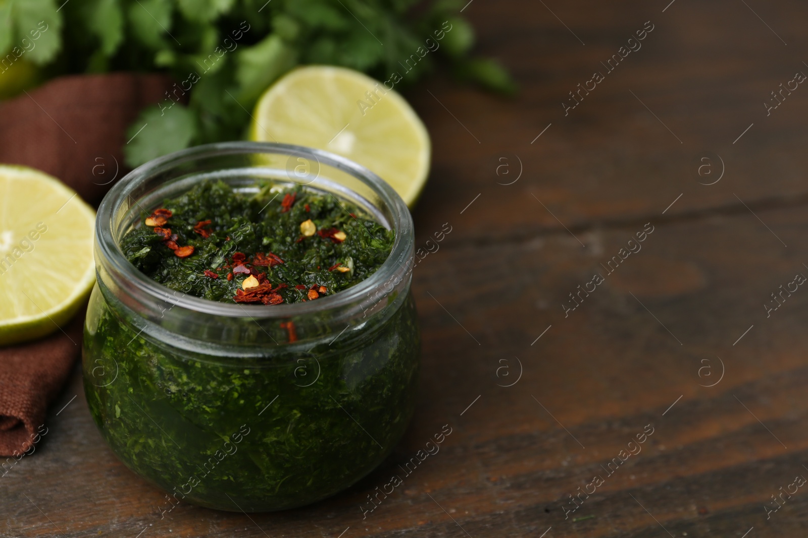 Photo of Tasty sauce with cilantro and lime on wooden table, closeup. Space for text