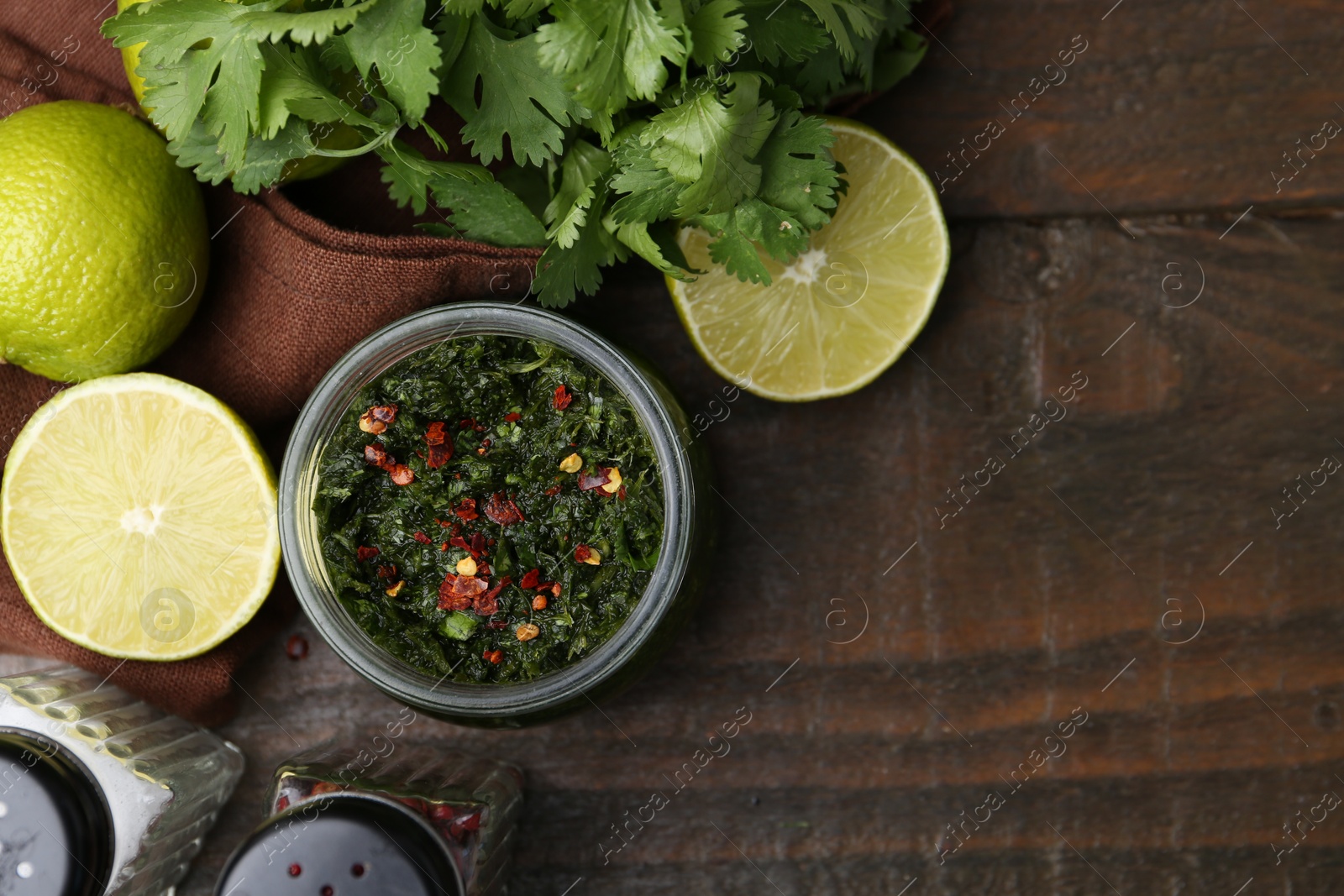 Tasty sauce with cilantro and limes on wooden table, flat lay. Space for text Photo of Tasty sauce with cilantro and limes on wooden table, flat lay. Space for text