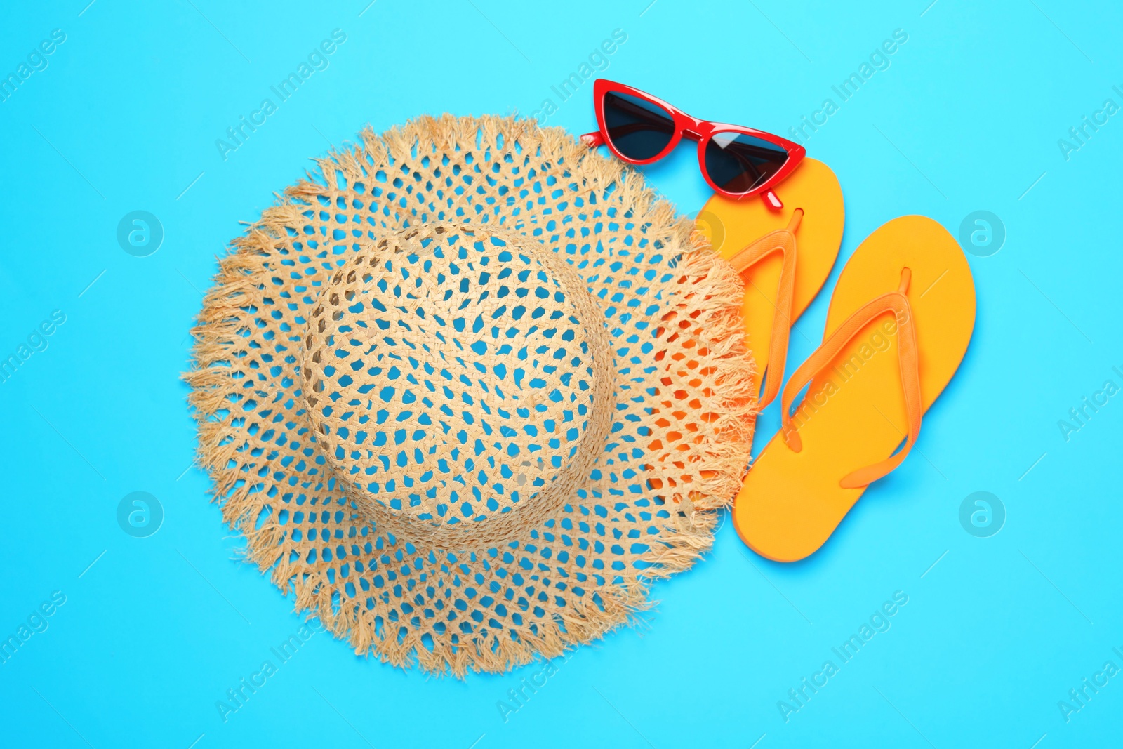 Straw hat, flip flops and sunglasses on light blue background, flat lay Photo of Straw hat, flip flops and sunglasses on light blue background, flat lay