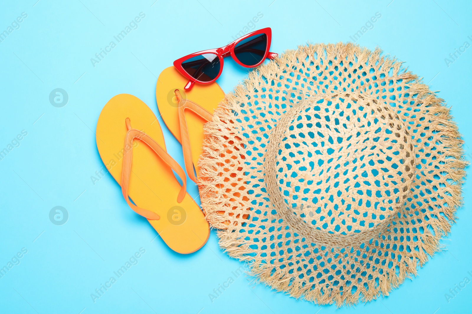 Straw hat, flip flops and sunglasses on light blue background, flat lay Photo of Straw hat, flip flops and sunglasses on light blue background, flat lay