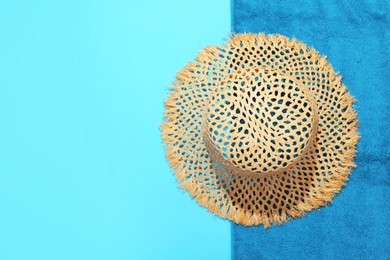 Photo of Straw hat and beach towel on light blue background, top view. Space for text