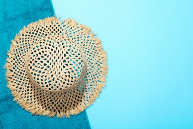 Photo of Straw hat and beach towel on light blue background, top view. Space for text