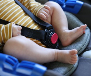 Photo of Cute little baby fastened in car seat, closeup