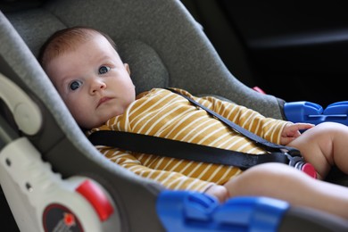 Photo of Cute little baby fastened in car seat