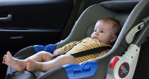 Photo of Cute little baby fastened in car seat