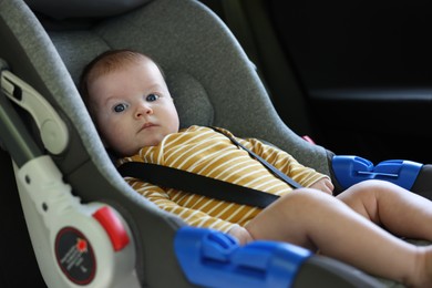 Photo of Cute little baby fastened in car seat