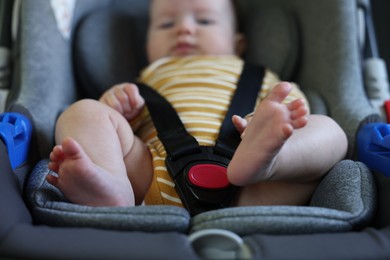 Photo of Cute little baby fastened in car seat, selective focus