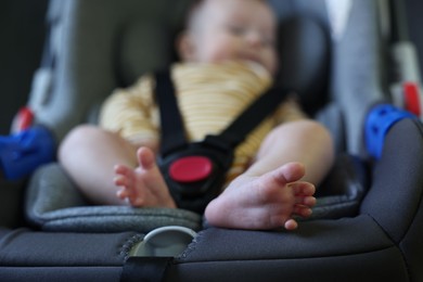 Photo of Cute little baby fastened in car seat, selective focus