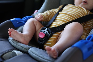 Photo of Cute little baby fastened in car seat, closeup