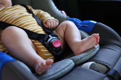 Photo of Cute little baby fastened in car seat, closeup