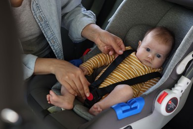 Photo of Mother fastening her baby in car seat, closeup