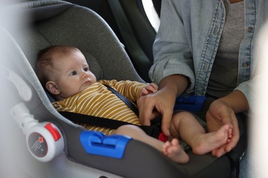 Photo of Mother fastening her baby in car seat, closeup