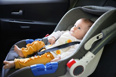 Photo of Cute little baby fastened in car seat