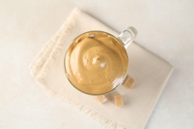 Photo of Delicious dalgona coffee in glass cup and brown sugar on light table, flat lay