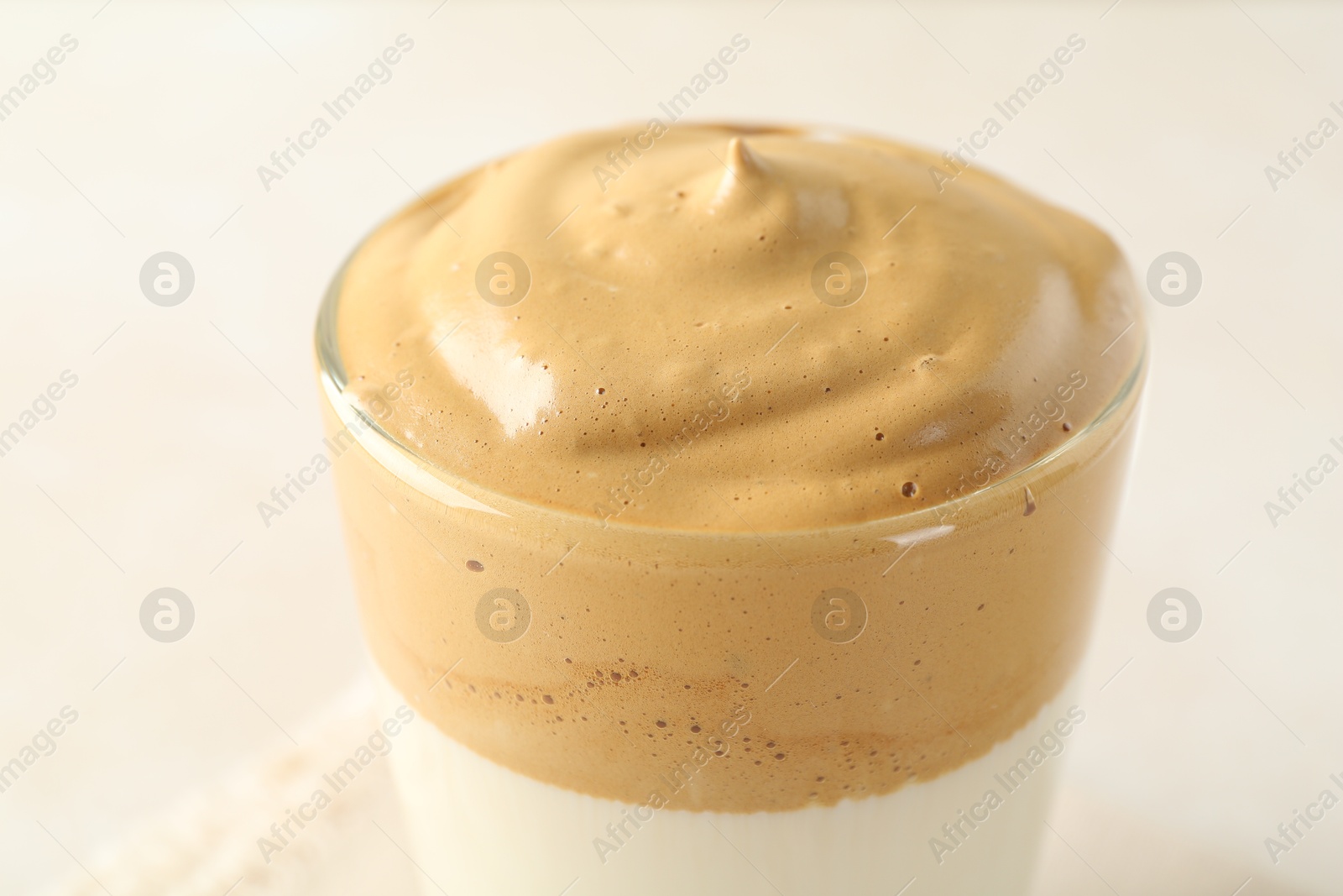 Photo of Delicious dalgona coffee in glass cup on light background, closeup