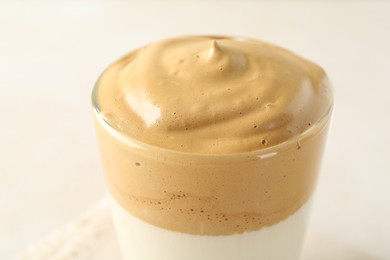Photo of Delicious dalgona coffee in glass cup on light background, closeup