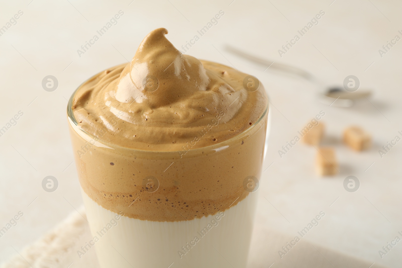 Photo of Delicious dalgona coffee in glass cup on light table, closeup