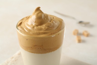 Photo of Delicious dalgona coffee in glass cup on light table, closeup